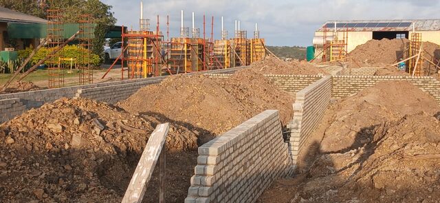 Wide view of brick retaining wall construction and Peri formwork columns on an Eastern Cape civil works site at golden hour
