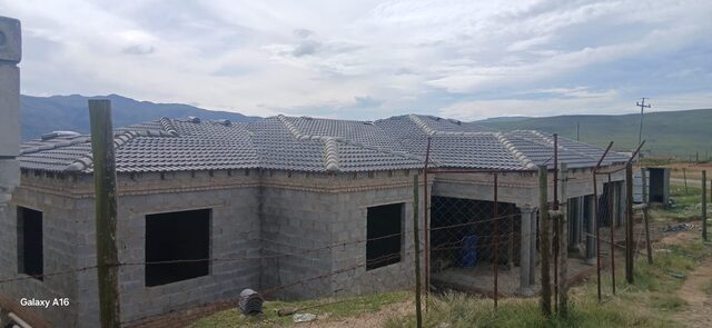 Large single-storey home with tiled roof and column verandah against Drakensberg mountain backdrop