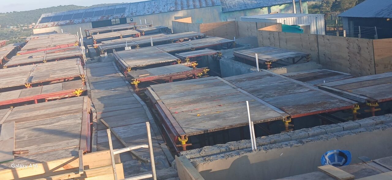 Aerial view of large suspended slab formwork with Peri red steel beams and yellow adjustable clamps across a full floor plate