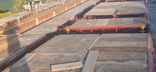 Close-up detail of Peri suspended slab formwork showing red steel runner beams and yellow adjustable clamp fittings